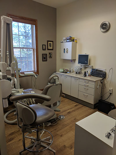 The image depicts a dental office interior with various pieces of equipment and furniture.